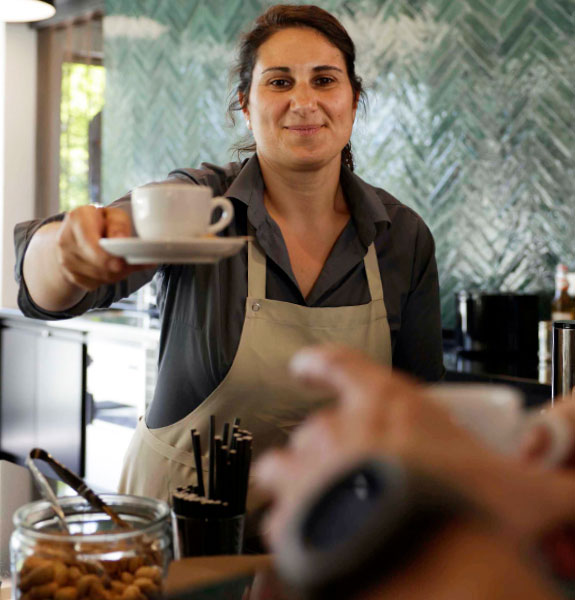 Mitarbeiterin gibt Kaffee an einen Kollegen